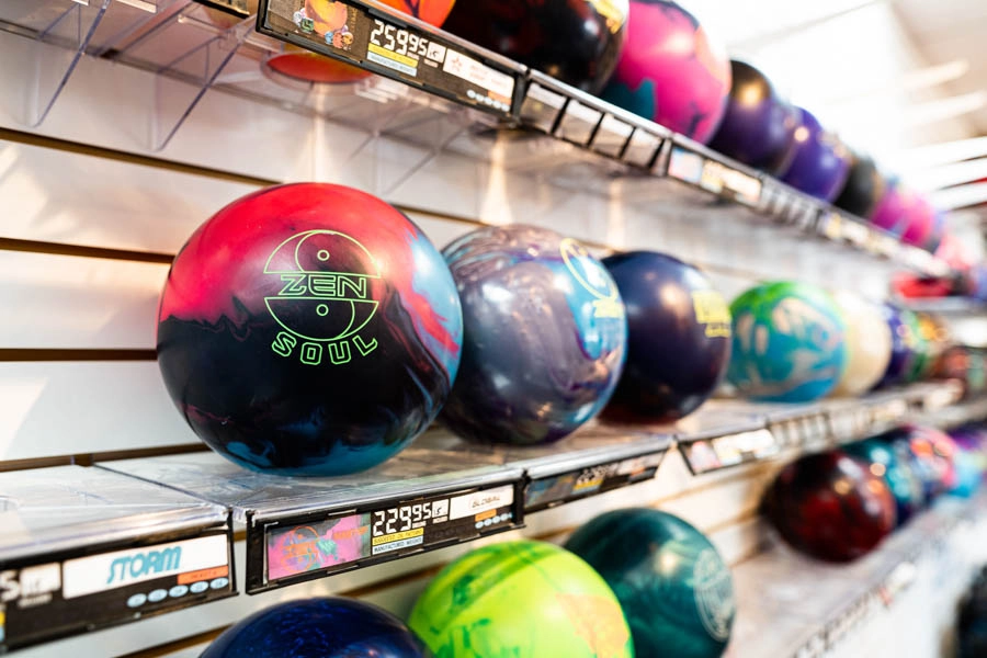 Close-up of colorful bowling balls displayed on racks in the pro shop
