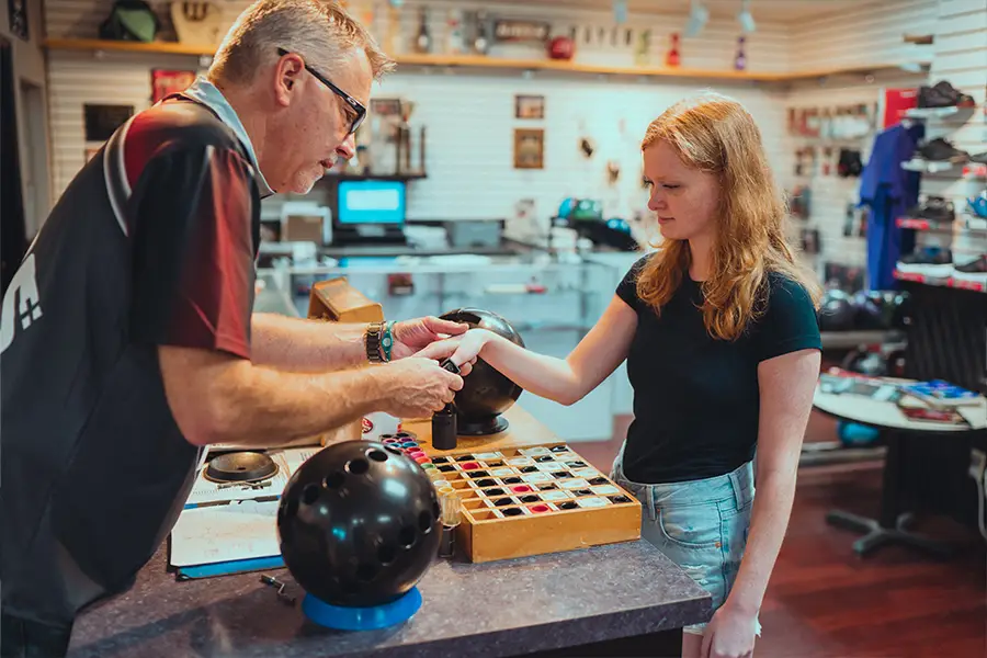 Bowlers' Shoppe staff member fitting a customer's hand for a bowling ball