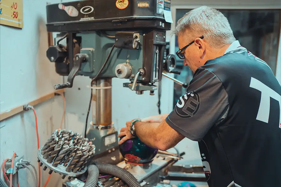 Pro shop technician working on a bowling ball using drilling equipment