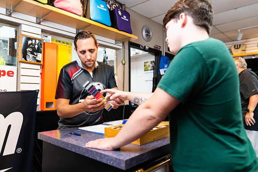 Customer reviewing colorful bowling ball inserts with a pro shop employee