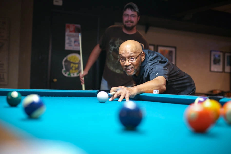 Man taking a shot during a game of pool at St. Clair Bowl