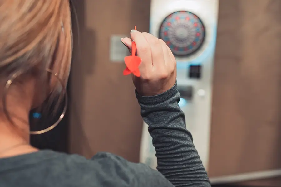 Woman preparing to throw a dart at an electronic dart machine