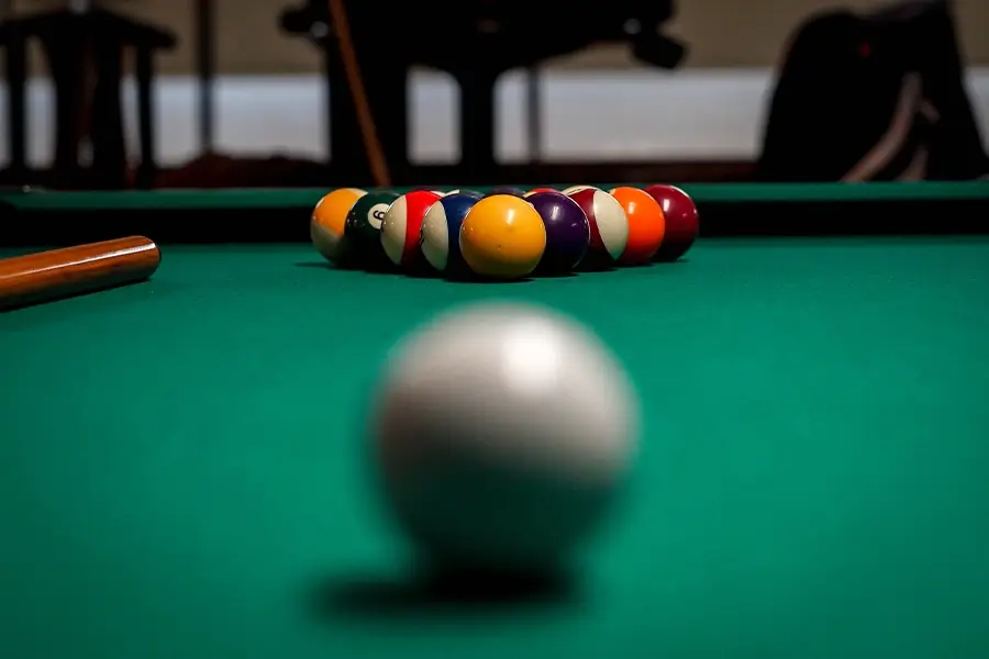 Racked billiard balls and cue ball on a green pool table