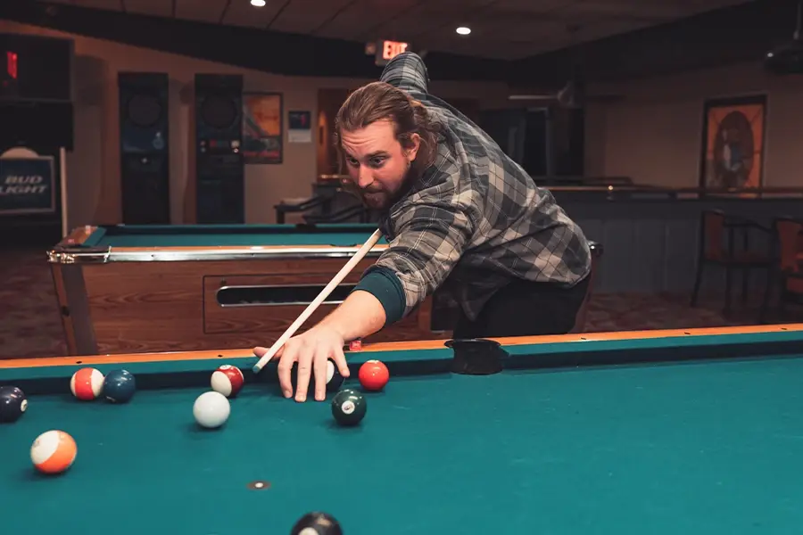 Man taking a shot on a pool table at St. Clair Bowl