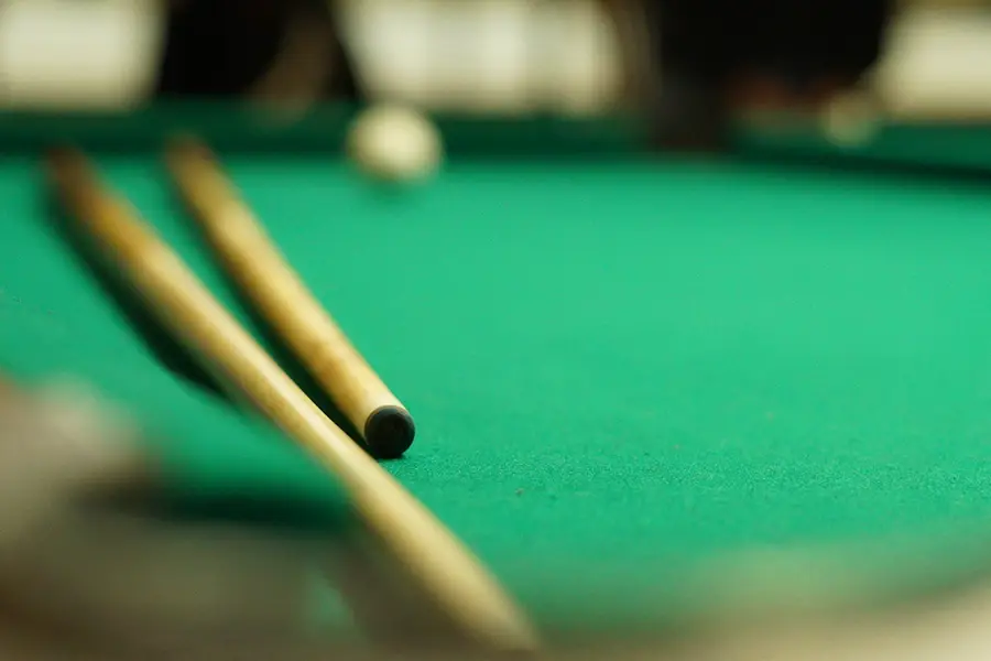 closeup image of pool sticks on a pool table
