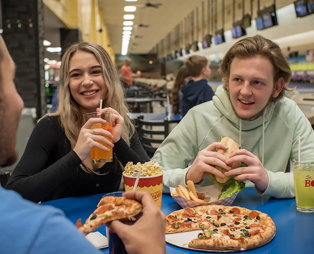 a couple of people eating food from Striker's Café at St. Clair Bowl in Fairview Heights IL