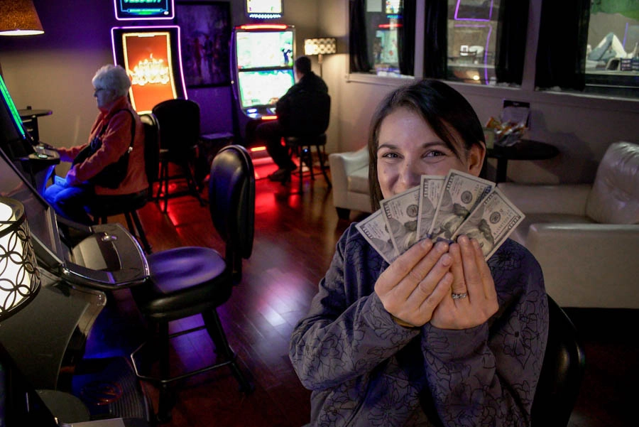 Woman holding cash after playing gaming machines at Trixie’s Gaming Parlor