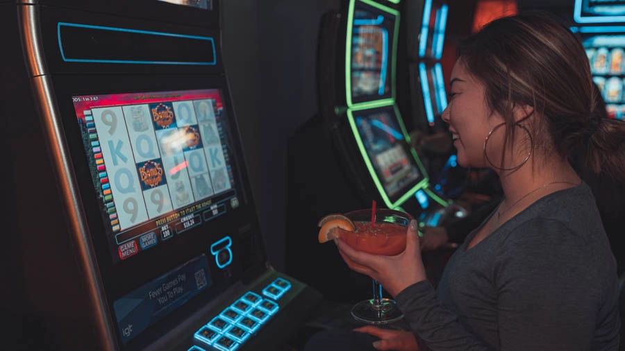 Woman enjoying a drink while playing a gaming machine