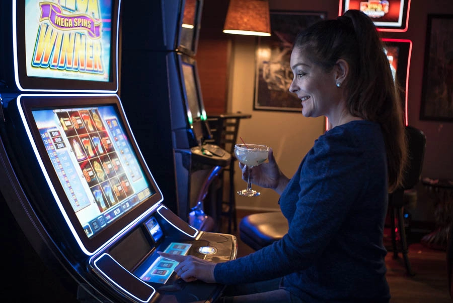Woman enjoying a gaming machine while holding a drink