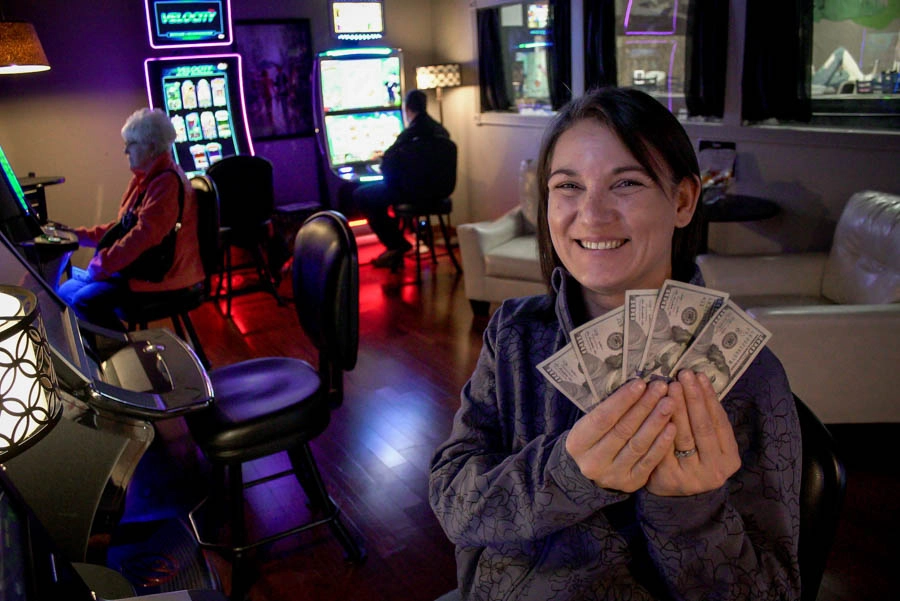 Woman smiling and holding cash inside Trixie’s Gaming Parlor
